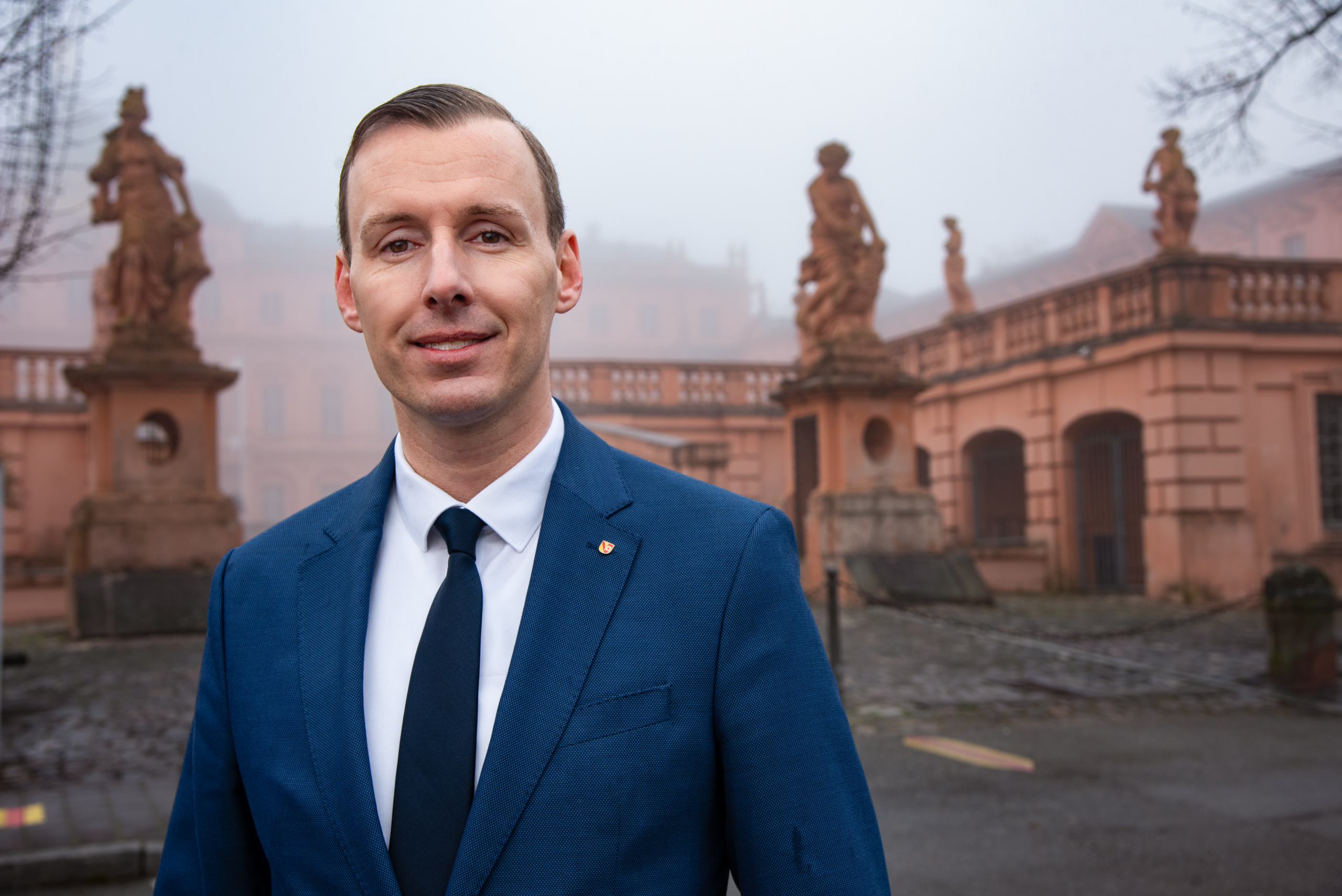 Landtagskandidat Philipp Helber (AfD) aus dem Wahlkreis Rastatt vor dem Barockschloss Rastatt – authentisches Porträt mit dem Schloss im Hintergrund und bürgernahem Charakter.